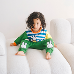 Kind, das das Bambus-Lounge-Set „Move“ in der Farbe Miffy mit einem Sweatshirt mit Fahrradmotiv und einer grünen Jogginghose trägt