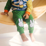 Kind, das das Bambus-Lounge-Set „Move“ in der Farbe Miffy mit einem Sweatshirt mit Fahrradmotiv und einer grünen Jogginghose trägt