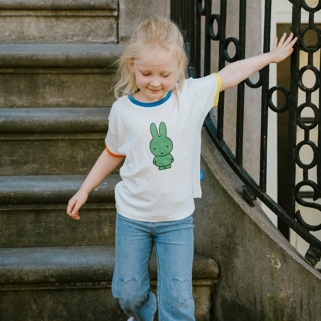 Kind, das das weiße Miffy Kinder-T-Shirt mit grünem Miffy Aufdruck trägt
