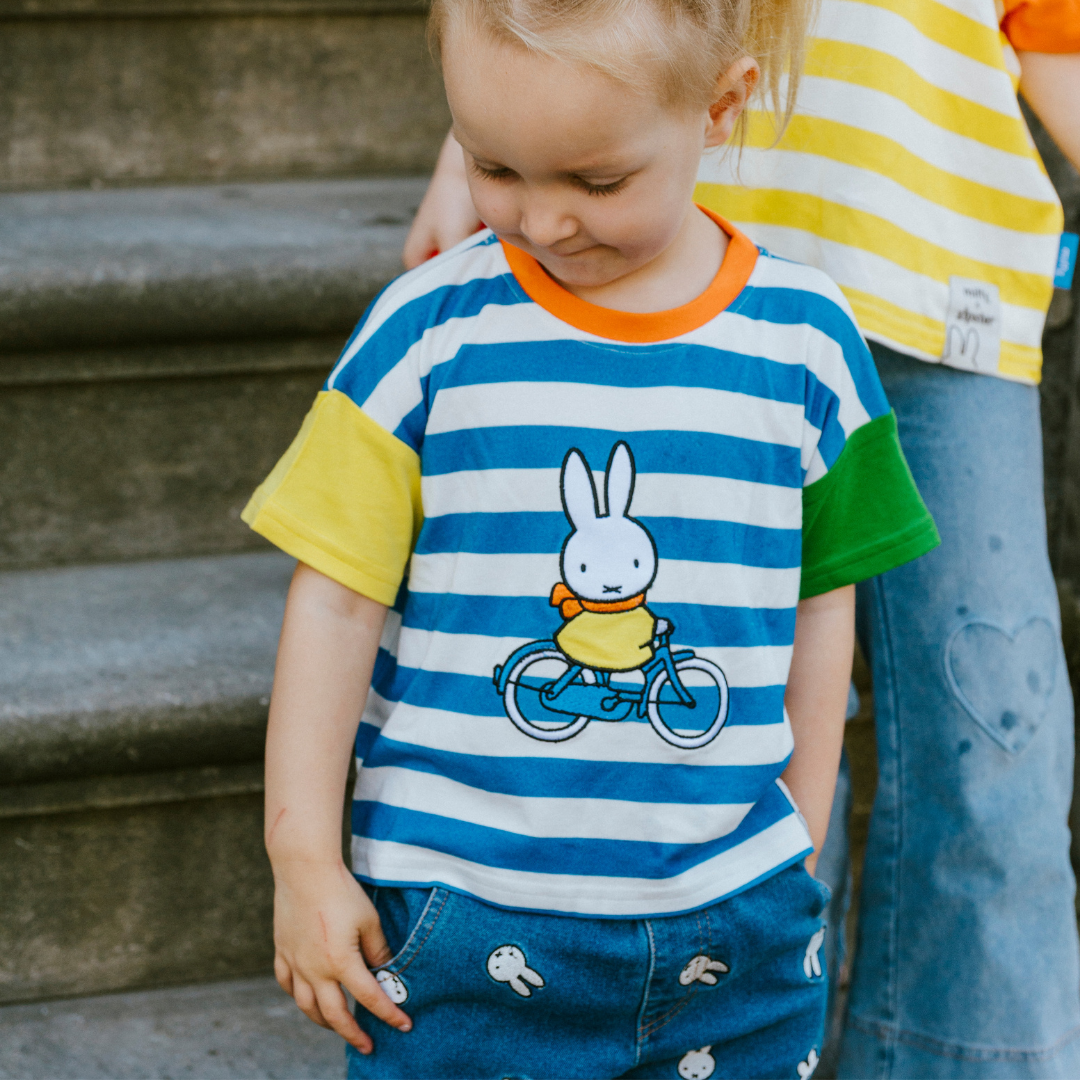 Kind, das das gestreifte „Move“-Kinder-T-Shirt mit Rippkragen in der Farbe Miffy trägt
